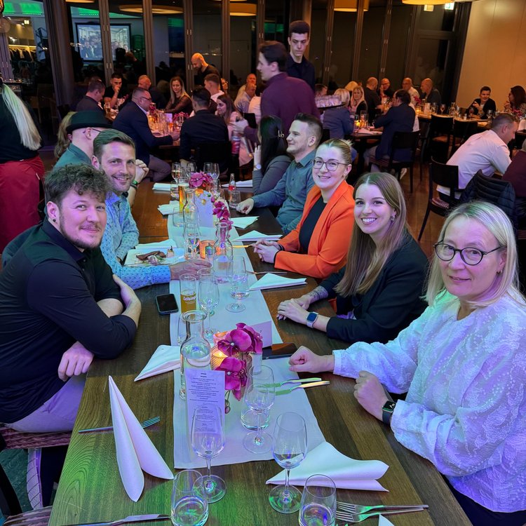Menschen sitzen an festlich gedeckten Tischen in einem großen Saal und genießen gemeinsam eine Abendveranstaltung.