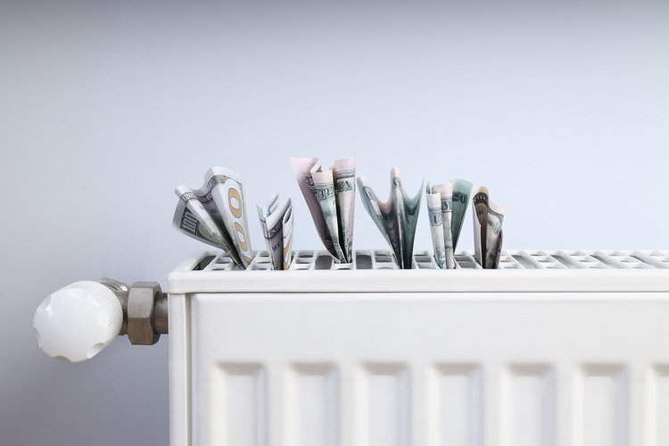 Mehrere Geldscheine stecken oben in einem weißen Heizkörper.