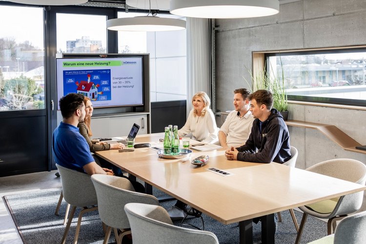 Mehrere Personen sitzen an einem Tisch in einem Besprechungsraum