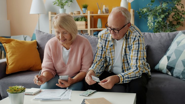 Älteres Paar überprüft Finanzen zu Hause auf der Couch.
