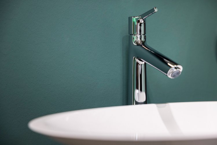 Ein Waschbecken mit Wasserhahn vor einer grünen Wand