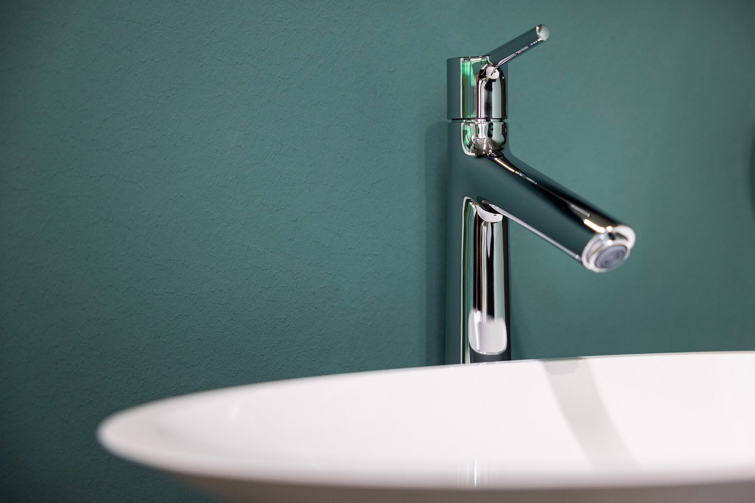 Team Hörmann Sanitär Ein Waschbecken mit Wasserhahn vor einer grünen Wand