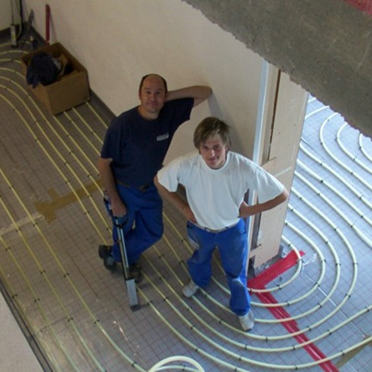 Zwei Mitarbeiter von Team Hörmann beim Verlegen der Heizschlaufen einer Fußbodenheizung im Jahr 2007
