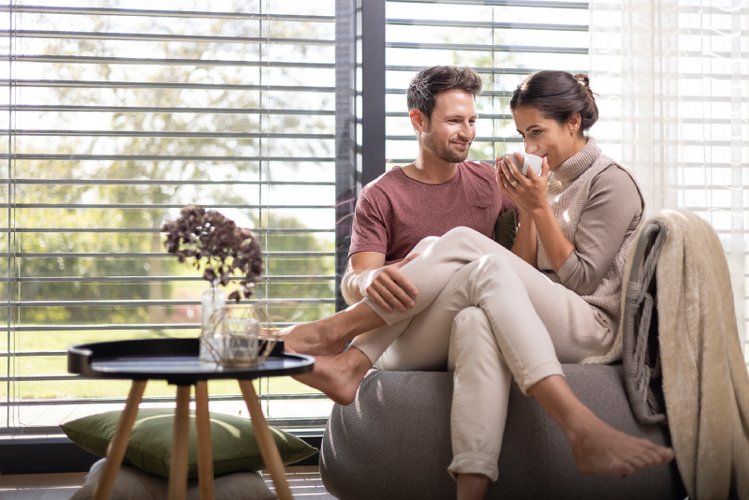 Paar zuhause Paar sitzt zuhause auf dem Sofa und trinkt ein warmes Getränk.