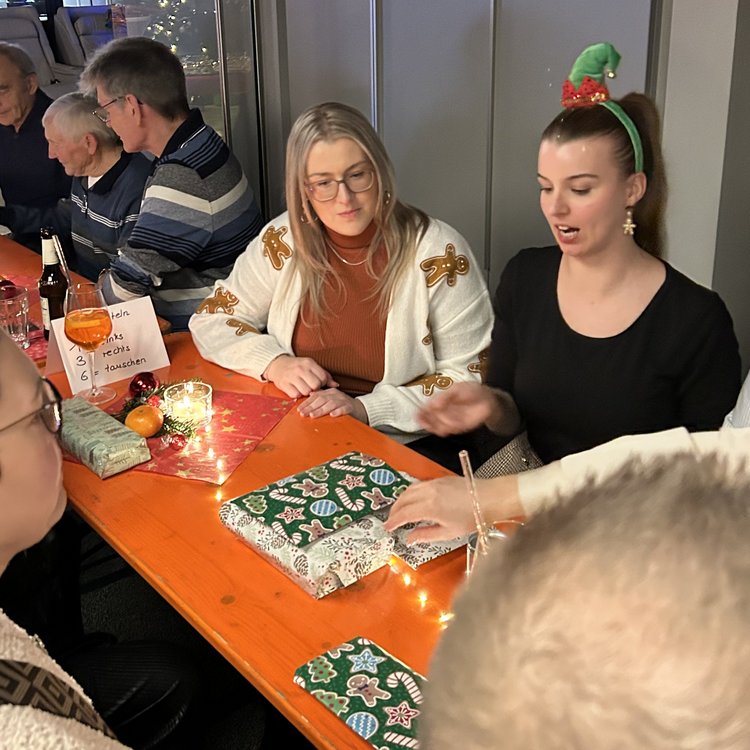 Mitarbeiter von Team Hörmann packen auf der Weihnachtsfeier gemeinsam Wichtelgeschenke aus.