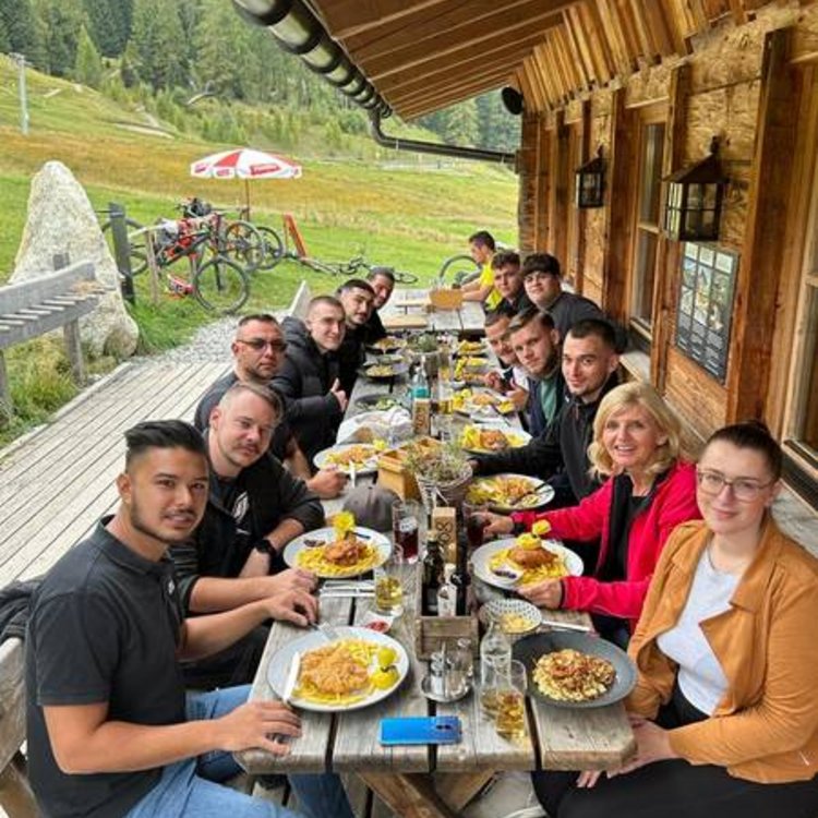 Mehrere Personen essen zusammen an einer Almhütte