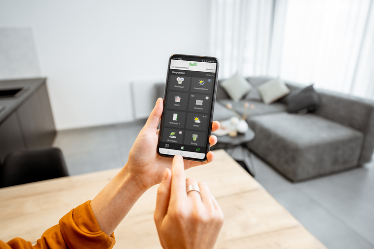 MyPelletronic App Eine Person hält ein Smartphone in der Hand: Darauf ist die MyPelletronic App geöffnet.
