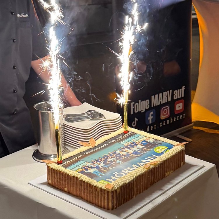 Festlich dekorierte Torte mit Bildmotiv und zwei brennenden Wunderkerzen, präsentiert auf einem Tisch bei 80-Jahr-Feier.