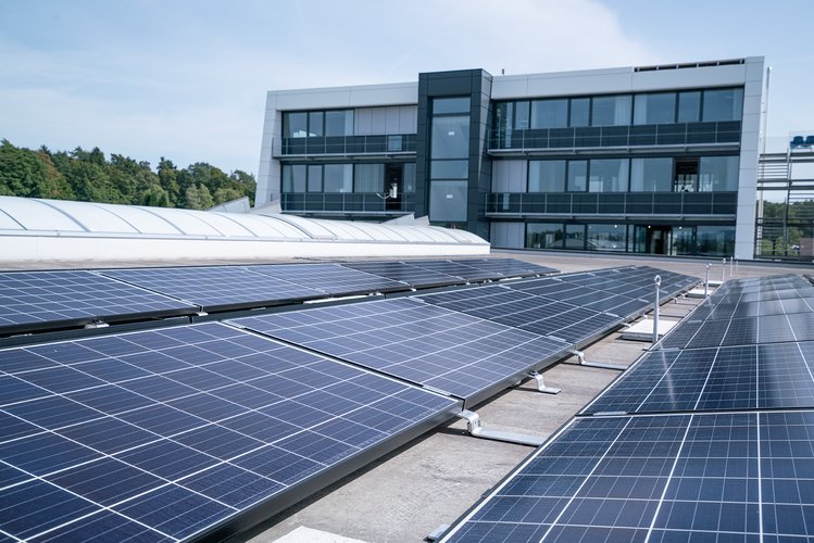 Solaranlage auf einem Flachdach mit Blick auf ein modernes Bürogebäude.